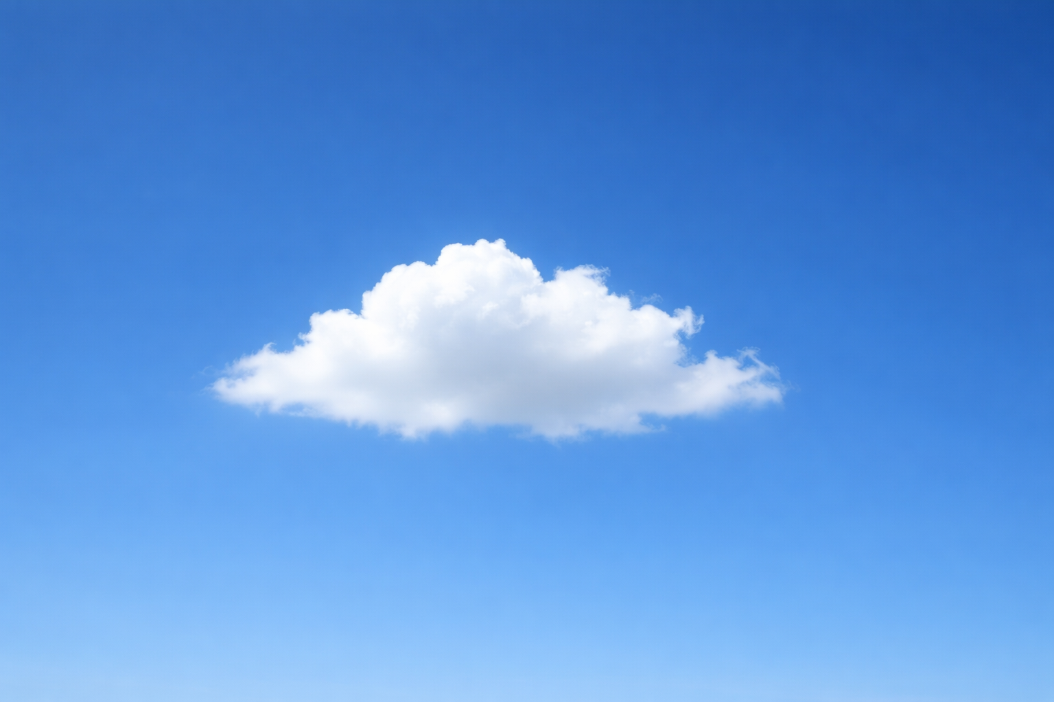 Eine einzelne, weiße, weich geformte Wolke schwebt vor einem klaren, kräftig blauen Himmel. Der Hintergrund zeigt einen sanften Farbverlauf von hellem zu dunklerem Blau ohne weitere Elemente.